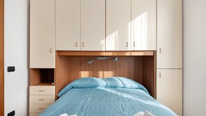 Un dormitorio con cama, cabecero de madera, armario y mesita de noche.