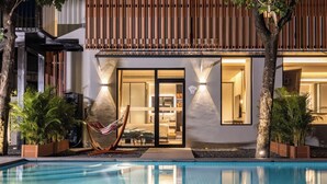 A modern hotel exterior with a swimming pool, a hammock, and a well-lit entrance. - Sanya Tufu Bay Scenic Yihai Hotel (Sanya)