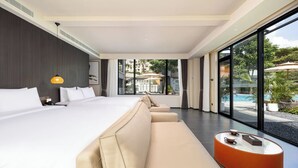 A modern hotel room with a large bed, a sofa, a small table, and a view of a swimming pool. - Sanya Tufu Bay Scenic Yihai Hotel (Sanya)