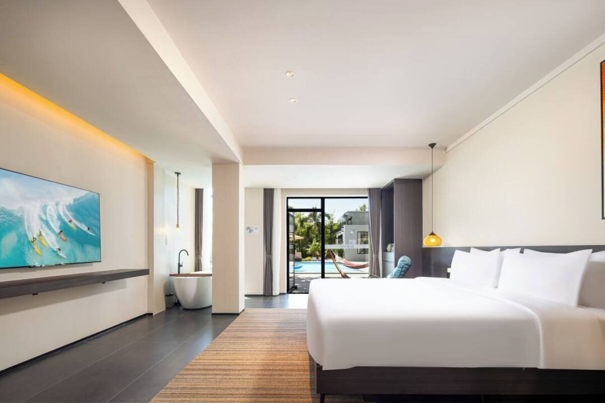 Quarto de hotel moderno com uma cama grande, TV de tela plana, banheira e vista para o exterior.