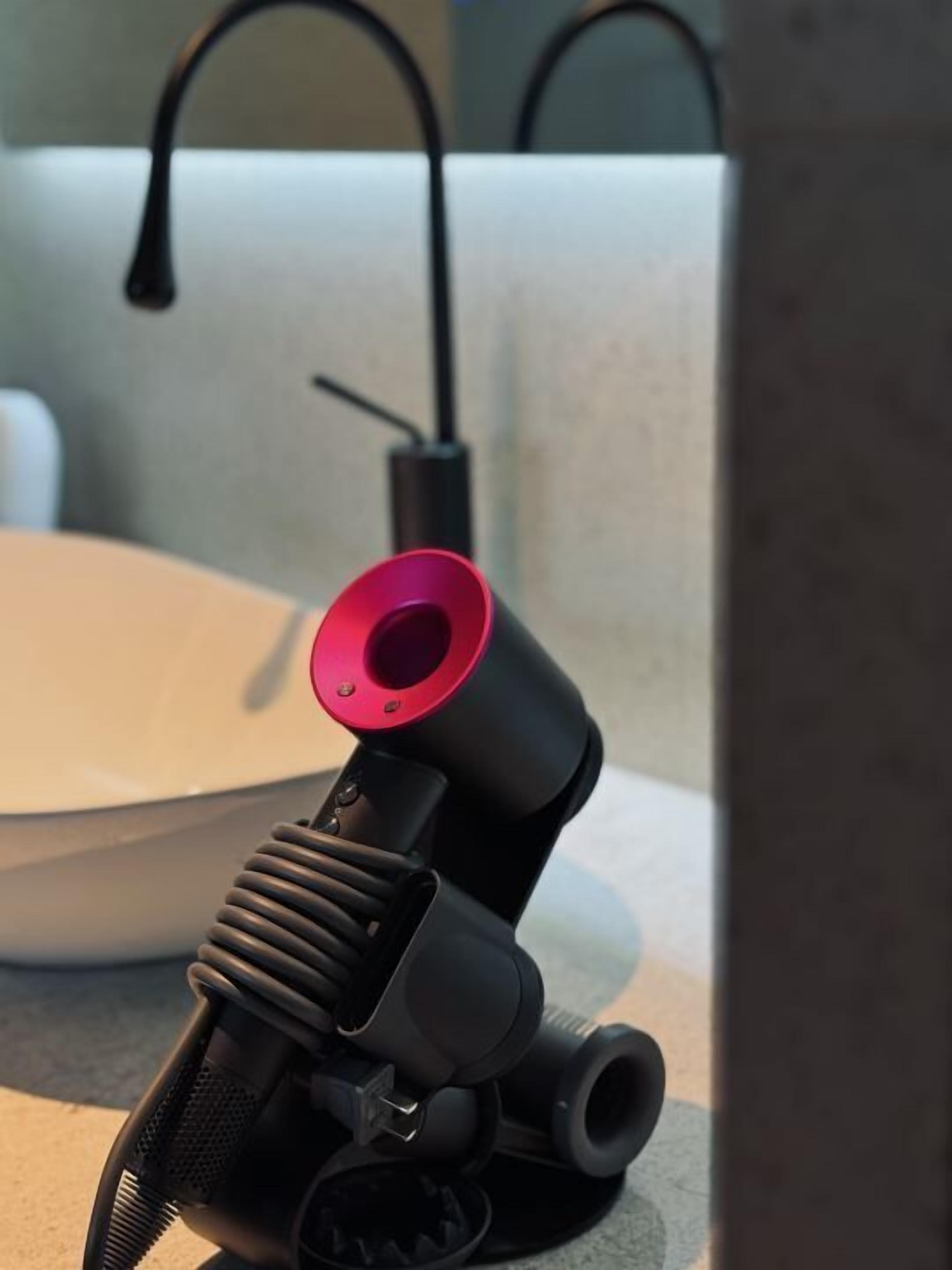 A bathroom with a white sink, a black faucet, and a red accent on the faucet.