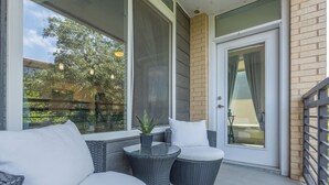 Un patio techado con mobiliario de mimbre, una mesa de vidrio y una planta en maceta.