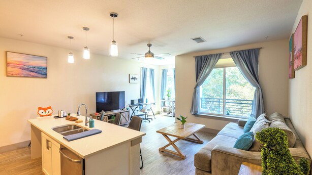 Una sala de estar moderna con un sofá, una mesa de comedor y una zona de cocina con un fregadero y un televisor.