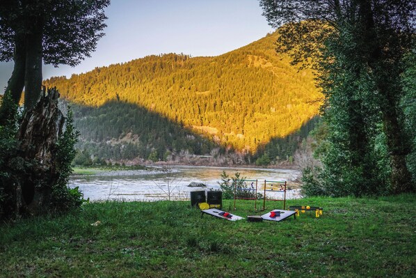 A camping area with a river, trees, and a mountain in the background.