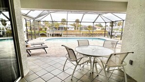 Eine überdachte Terrasse mit Pool, Sitzgelegenheiten im Freien und Deckenventilator.