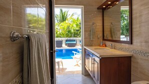 Un baño con un espejo grande, un lavamanos y vistas a una zona de piscina al aire libre.