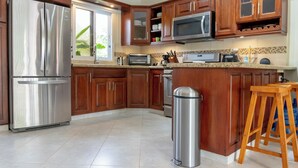 Una cocina moderna con electrodomésticos de acero inoxidable, armarios de madera y salpicadero de azulejos.