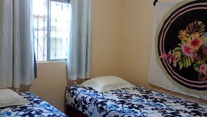 A room with two beds, a window with curtains, and a wall tapestry. - Pousada Alecrim (Santarém)