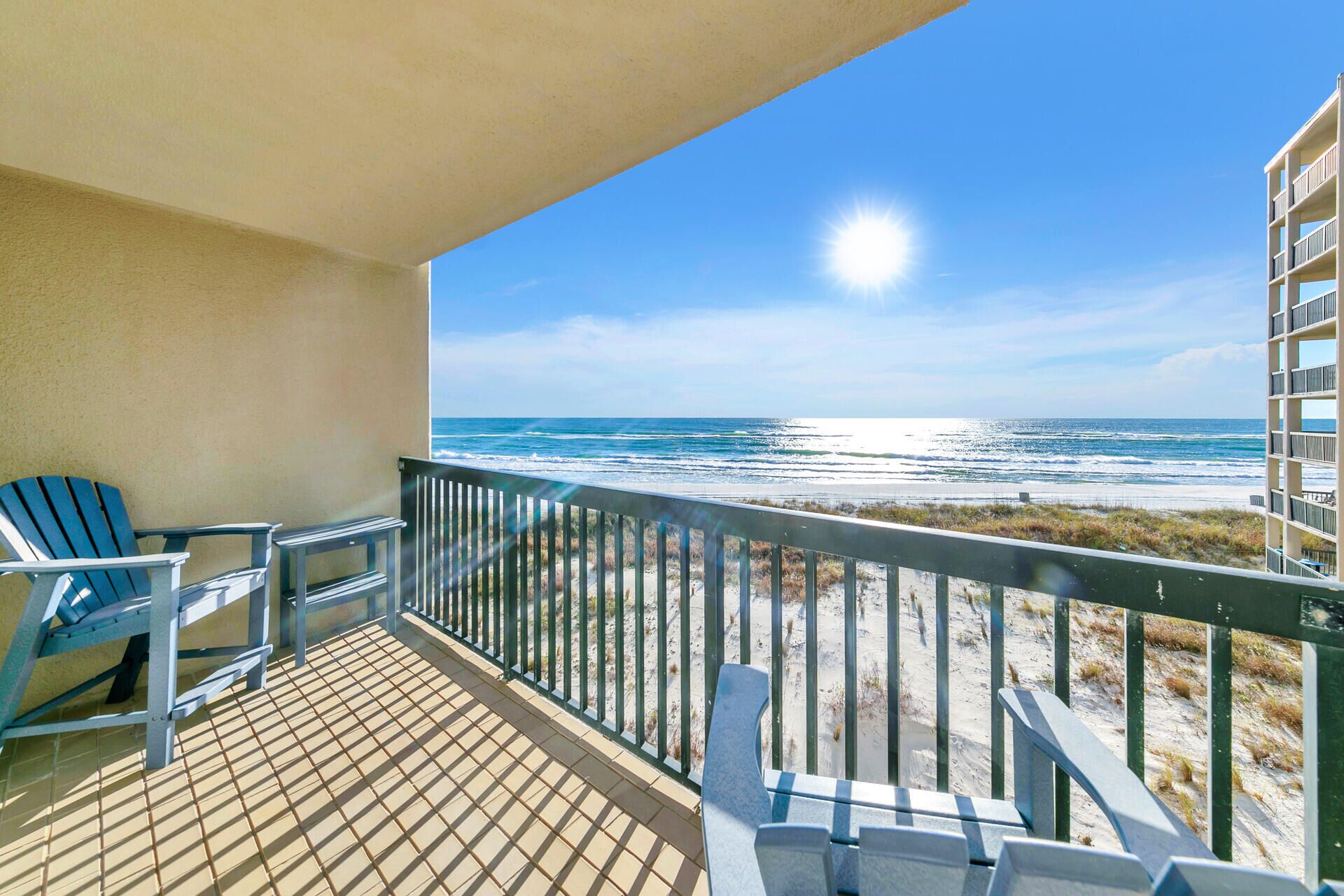 Een balkon met uitzicht op het strand, een stoel en een tafel.