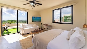 A bedroom with a bed, a ceiling fan, a desk, and a view of the outdoors. - Studio 55 Private HotTube (Puerto Aventuras)