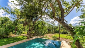 A swimming pool surrounded by lush greenery and trees. - Studio 55 Private HotTube (Puerto Aventuras)