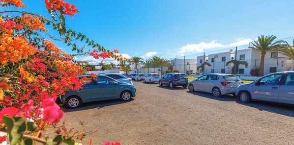 Un estacionamiento con varios autos y un edificio al fondo.