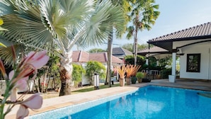 A swimming pool with a tiled deck, surrounded by palm trees and potted plants. - Kesorn Charming Authentic Thai Pool Villa Phuket (Rawai)