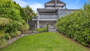 A modern two-story house with a covered front porch and a well-maintained garden. - Ocean View Spacious 5BR Retreat for Families (Auckland)