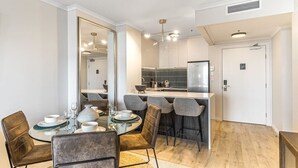A modern dining area with a round table, chairs, and a kitchen in the background.
