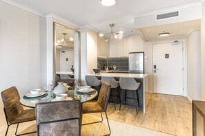 Un espace repas moderne avec une table ronde, des chaises et une cuisine en arrière-plan.