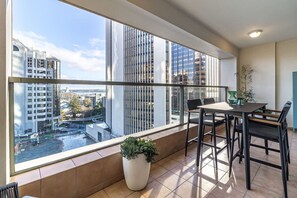 A modern apartment with a balcony, large windows, and a dining area with a table and chairs.