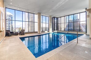 A large indoor swimming pool with clear views of the cityscape through large windows.