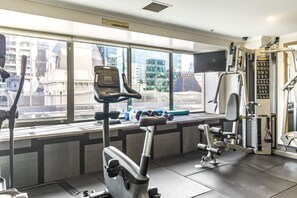 Une salle de sport équipée de machines d’exercice, d’un tapis de course et d’haltères.