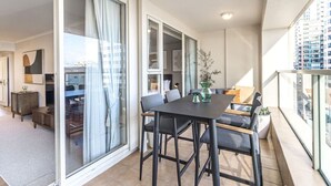 A modern apartment with a balcony, a dining area, and a living room with a sofa and a coffee table.