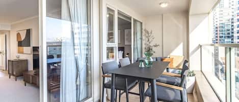Un apartamento moderno con balcón, comedor y sala de estar con sofá y mesa de centro.