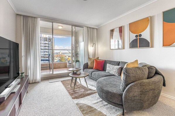 A modern living room with a gray sofa, a small round table, and a TV.