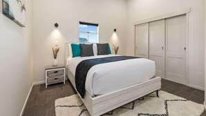 A bedroom with a bed, bedside tables, a window, and a wardrobe. - Stay Devonport - 3 Bedroom Penthouse (Auckland)