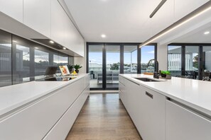 Une cuisine moderne dotée d’un îlot central, de grandes fenêtres et offrant une vue sur le paysage urbain.