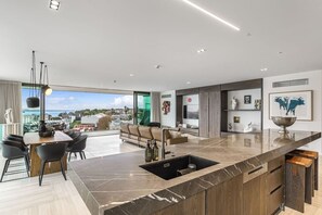Una cocina moderna con encimera de mármol, pileta integrada y comedor con vistas.