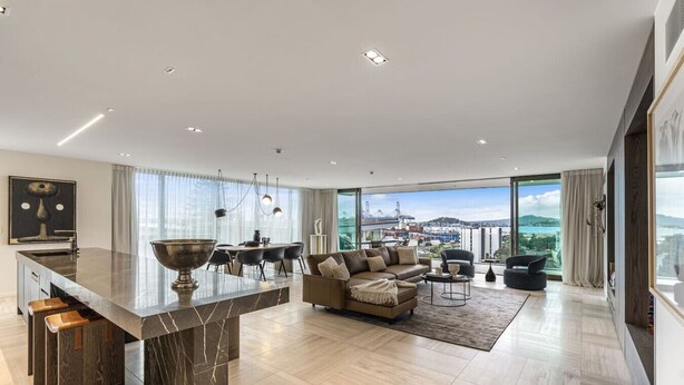 A modern living room with a large island, a sofa set, and a view of a cityscape.