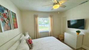 A bedroom with a bed, a ceiling fan, a TV, and a window with curtains. - NEW Amazing Sunshine-Up 6 Guests-Private Backyard (Port Orange)