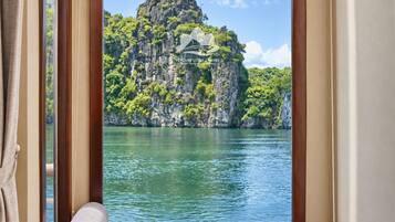 Una habitación con ventana que da a una masa de agua y un paisaje montañoso.