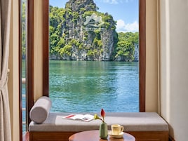 Una habitación con ventana que da a una masa de agua y un paisaje montañoso.