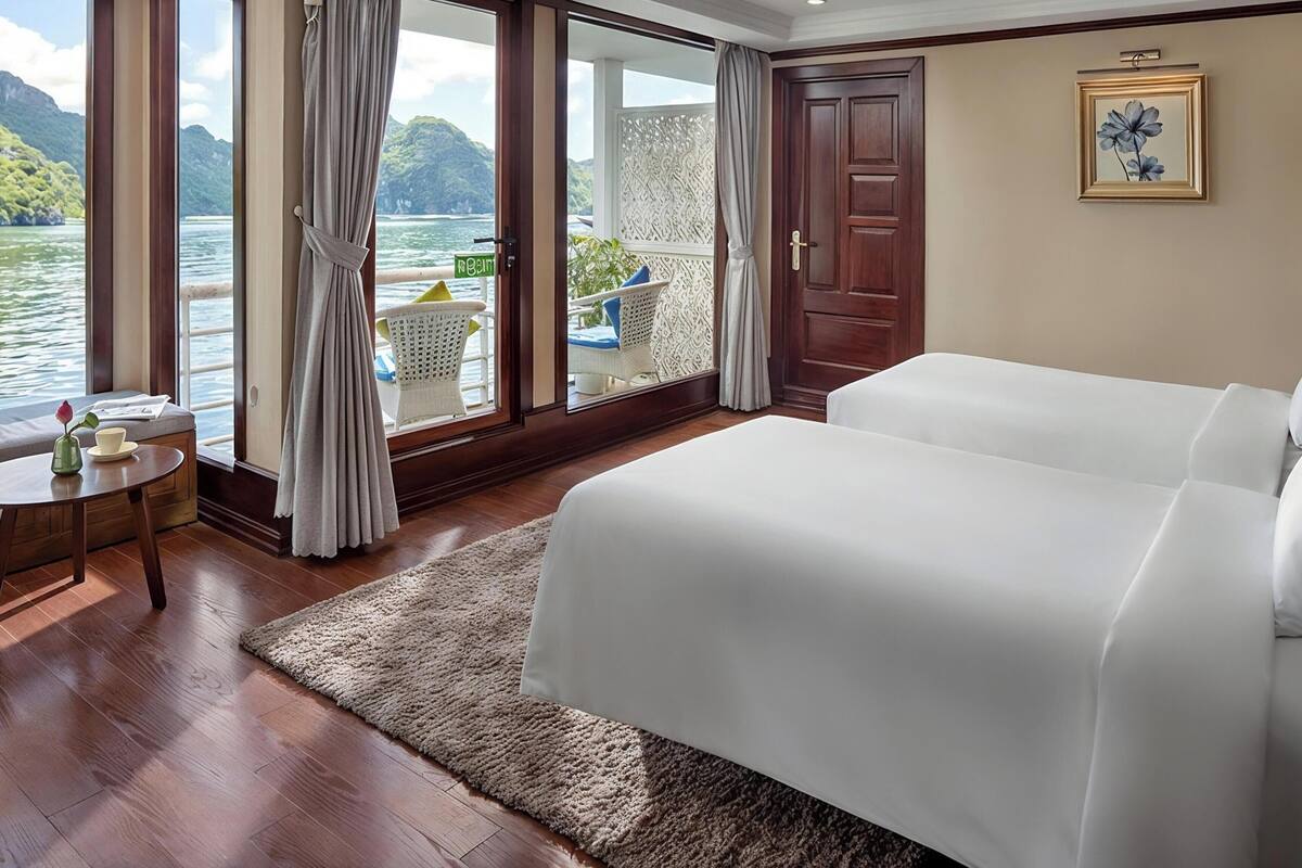 A hotel room with a bed, a small table with a vase and cup, a view of the sea, and a door with a sign.