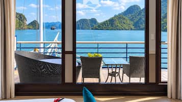 A room with a large window offering a view of a body of water and mountains.