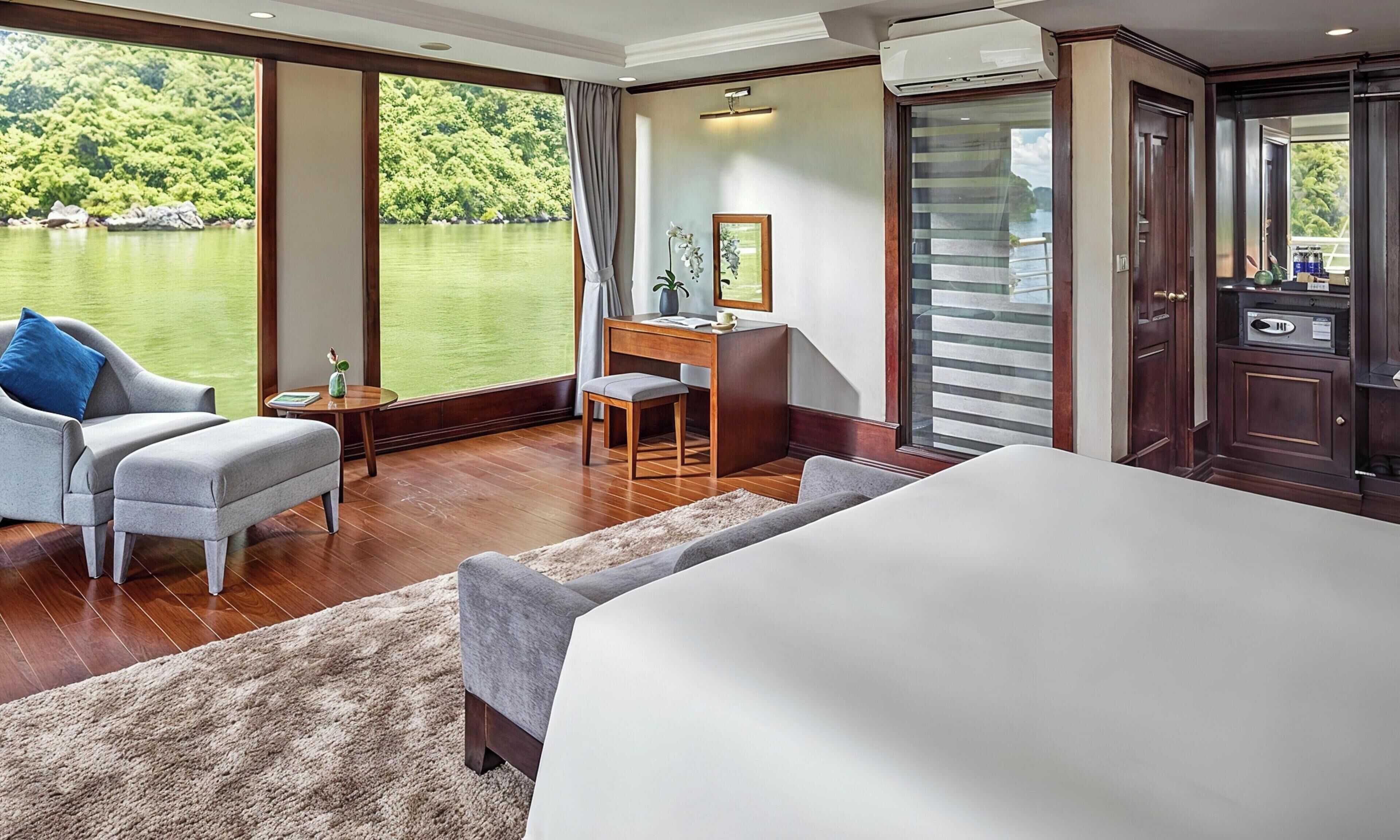 A hotel room with a large bed, a desk, a chair, a small table, and a view of a lake.