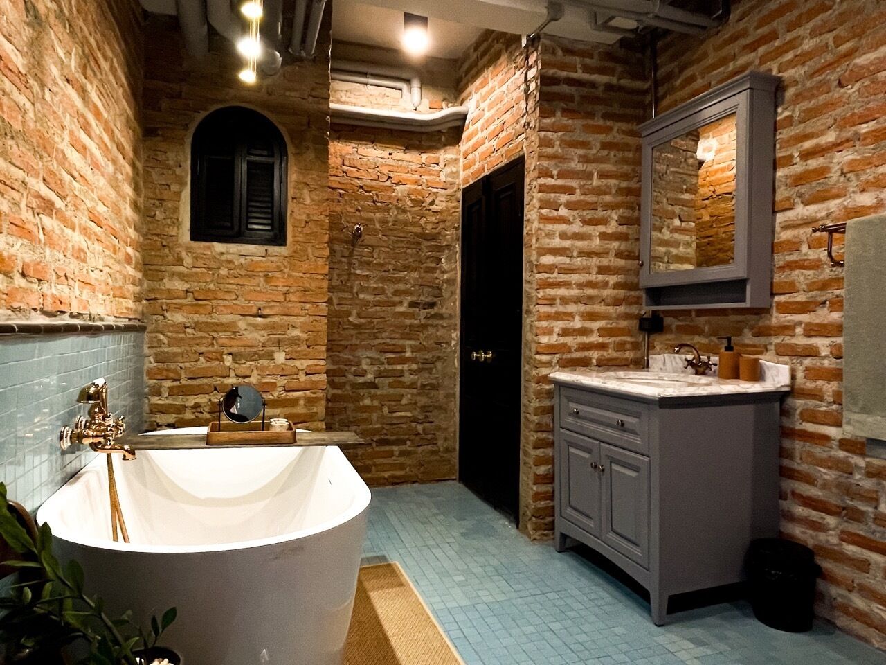 A bathroom with a freestanding bathtub, a vanity with a mirror, and a door leading to another room.