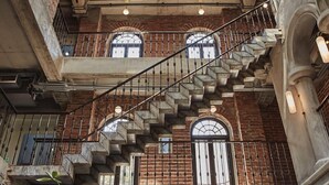 A multi-level interior with a central staircase, brick walls, and arched windows. - Cataleya Estate Boutique Hotel (Bangkok)