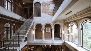 A multi-level interior with a staircase, arched windows, and a dining area. - Cataleya Estate Boutique Hotel (Bangkok)