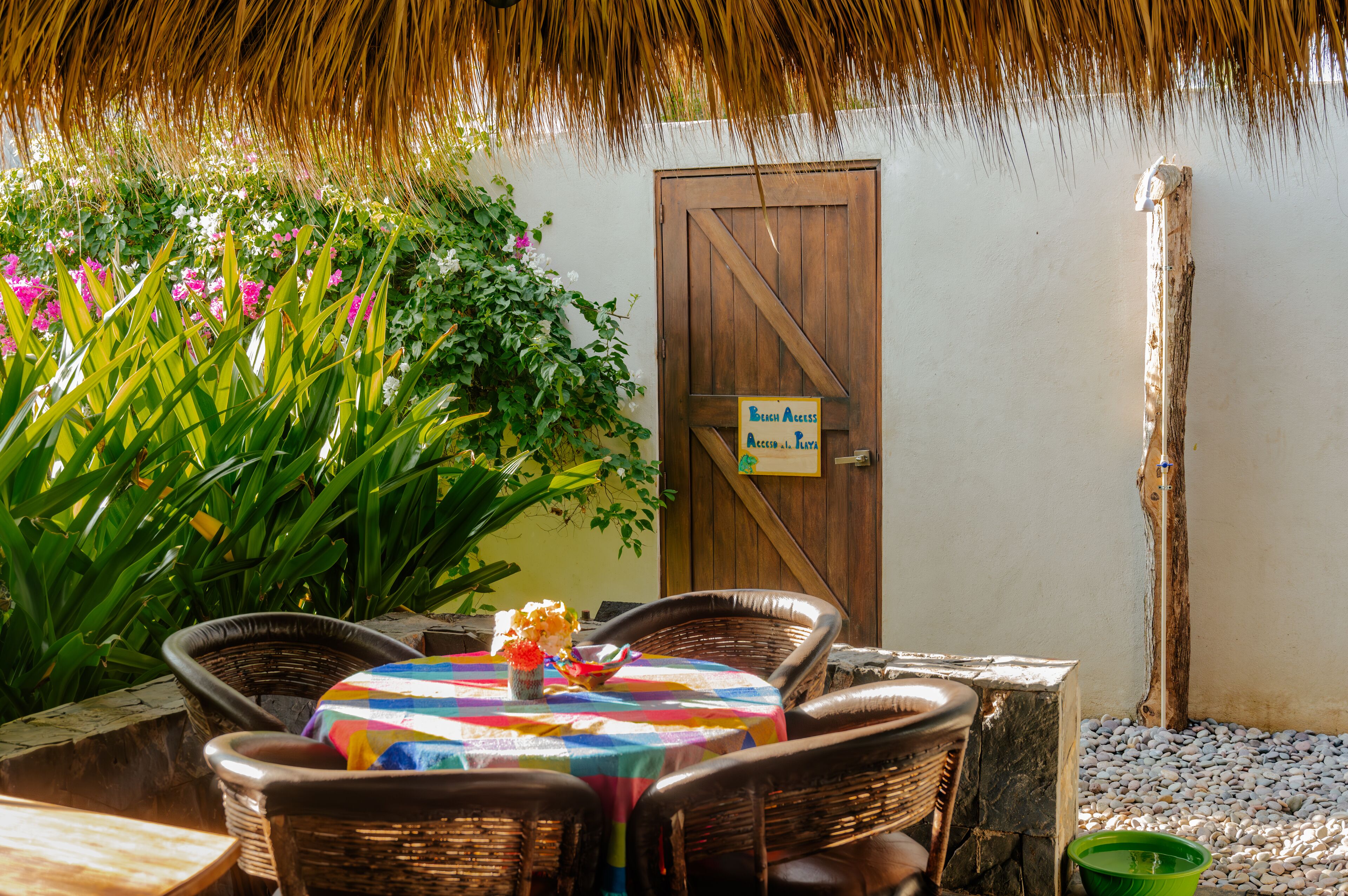 Un espacio al aire libre con sillas de mimbre y una mesa cubierta con un mantel colorido.