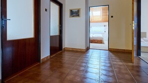 A hallway with wooden doors, a tiled floor, and a view into a bedroom with a bed and window. - Vacation home Burger by Interhome (Harrachov)