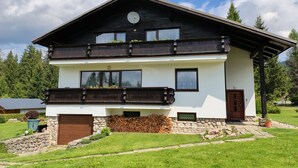 A two-story house with a balcony, a stone wall, and a well-maintained lawn. - Vacation home Burger by Interhome (Harrachov)
