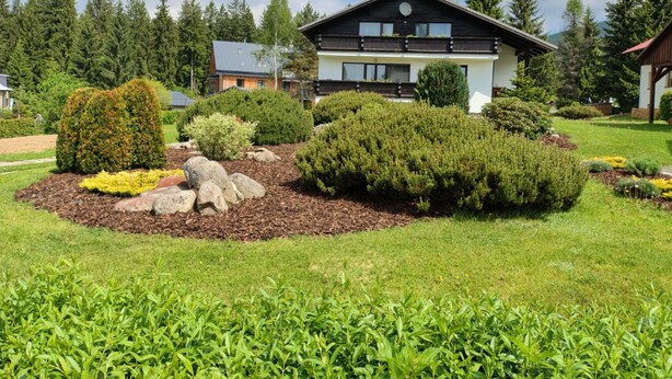 A modern two-story house with a well-maintained garden featuring various shrubs and a rock centerpiece. - Vacation home Burger by Interhome (Harrachov)