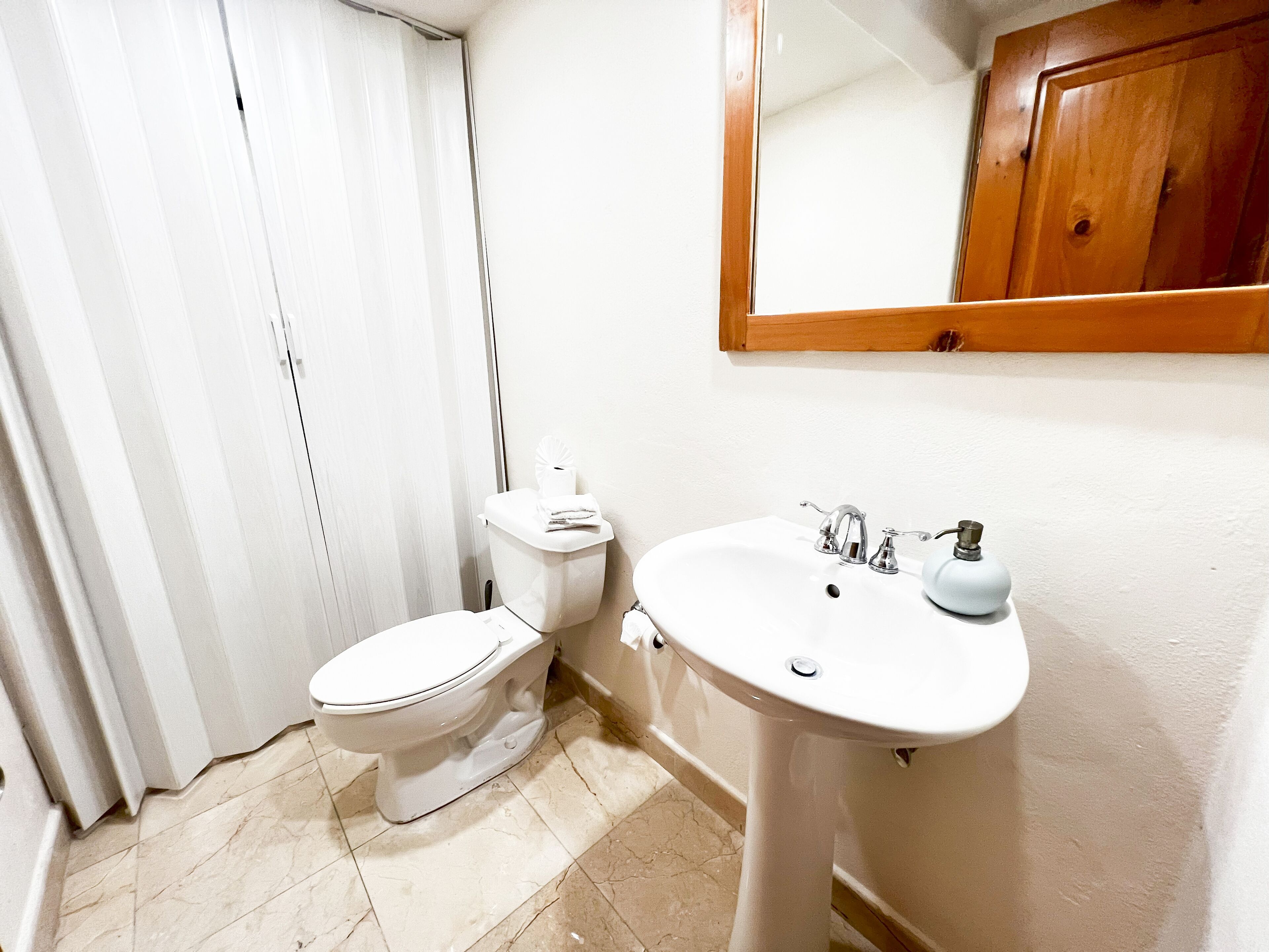 A bathroom with a toilet, sink, and mirror.