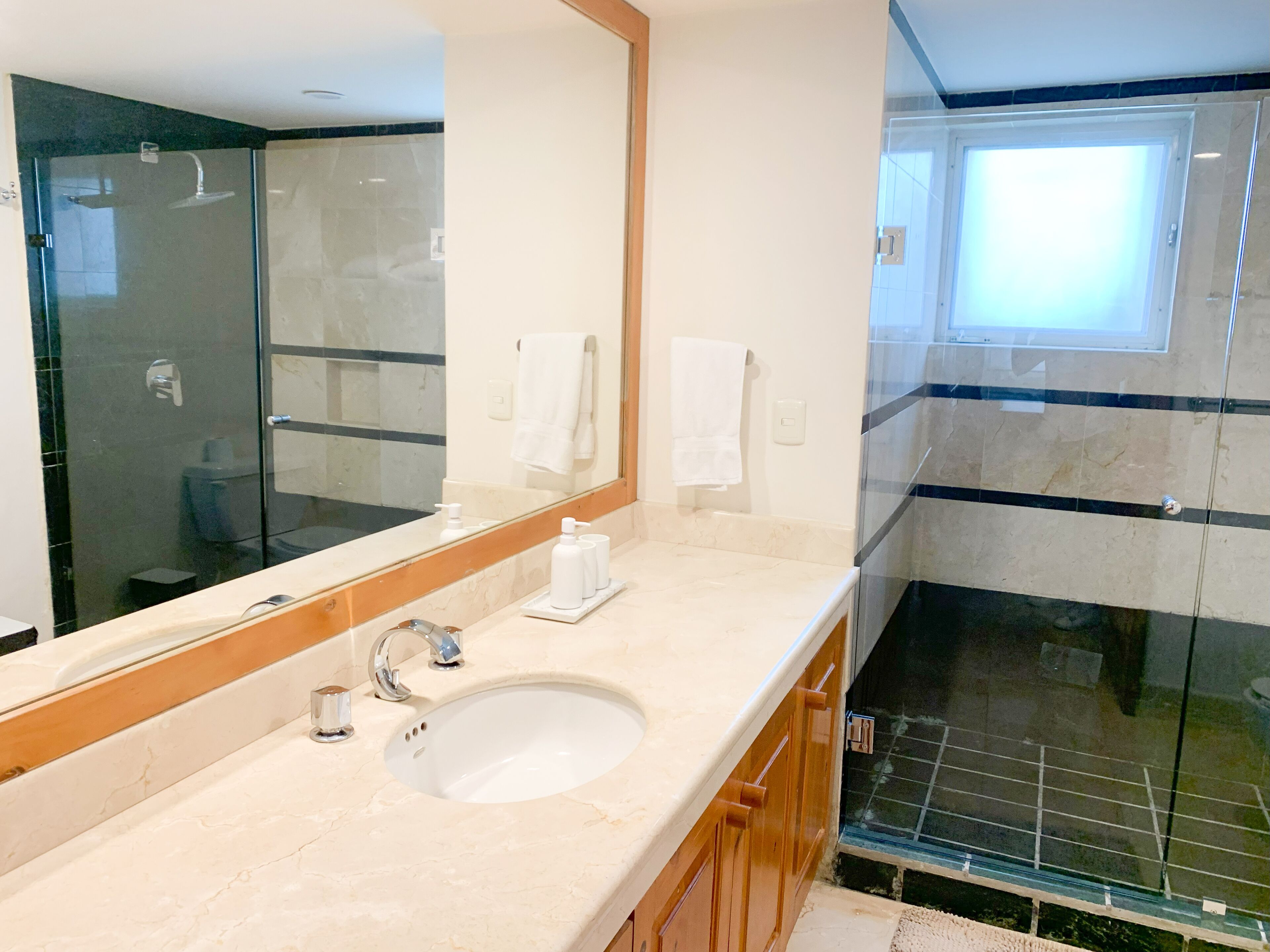 Un baño moderno con un espejo grande, un lavabo y una zona de ducha.