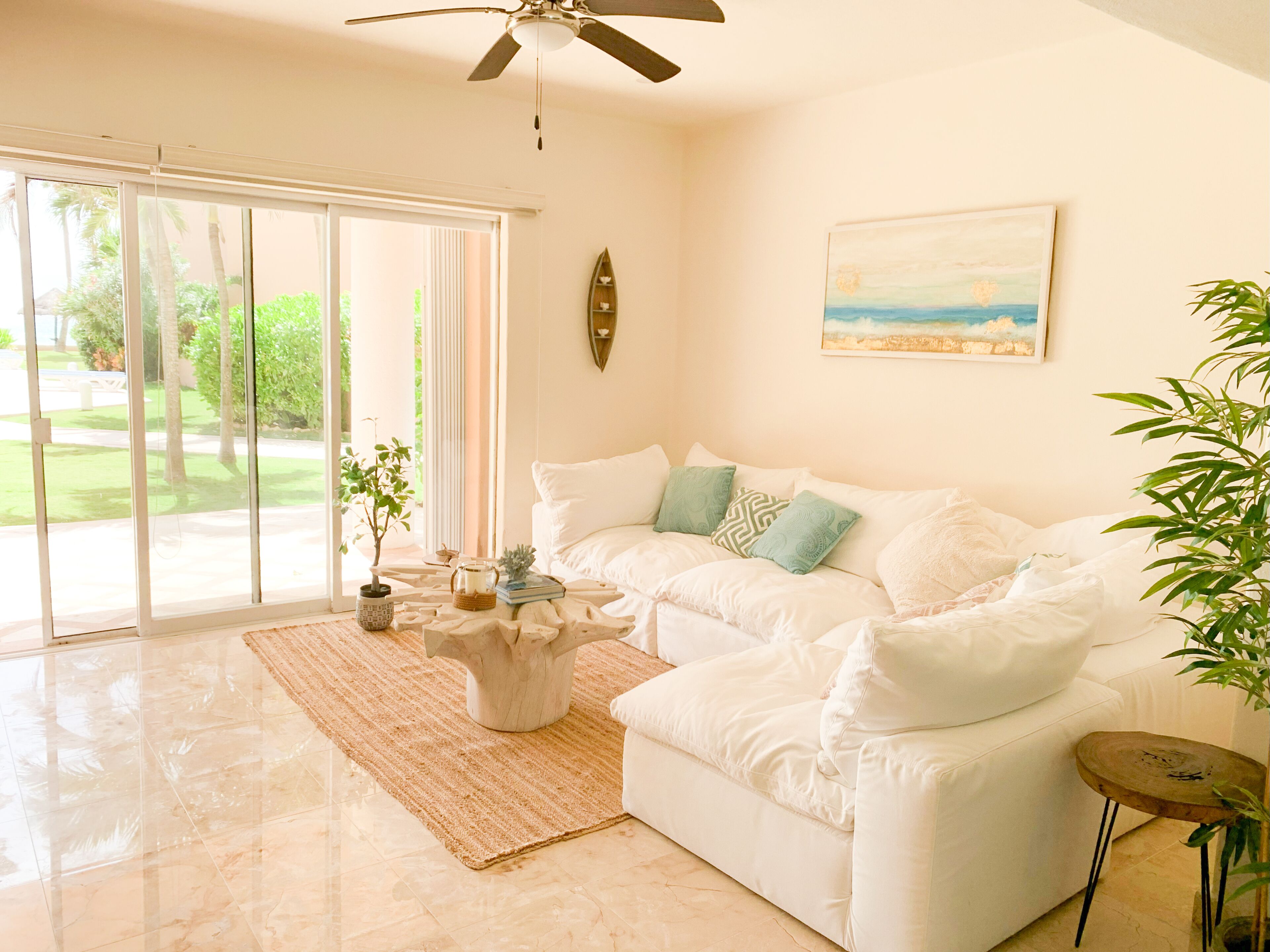 A spacious living room with a white sofa, a coffee table, and a painting on the wall.