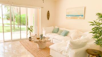 A spacious living room with a white sofa, a coffee table, and a painting on the wall.