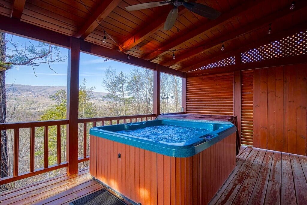 A wooden deck with a hot tub, wooden railings, and a view of the landscape.
