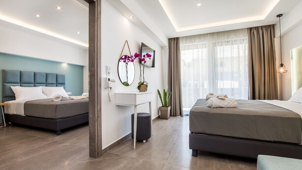 A modern hotel room with two beds, a desk, a TV, and a large window with curtains.