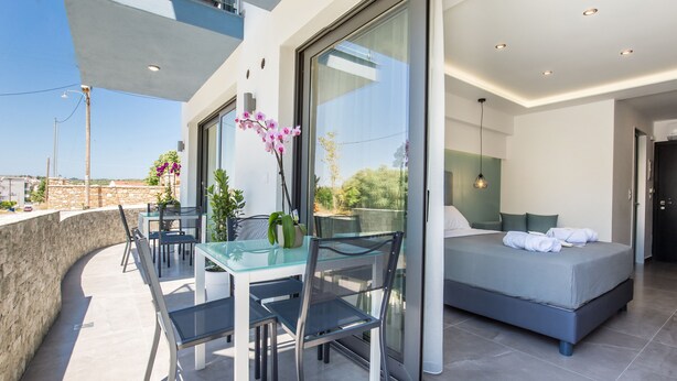 Un balcon moderne avec une table et des chaises en verre, un lit avec des oreillers et une vue sur le paysage.